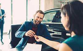 Salesperson handing man keys to new car.